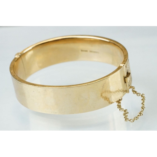 36 - 9ct yellow gold hinged bangle, engraved foliate scroll decoration to the upper half, tongue and box ... 