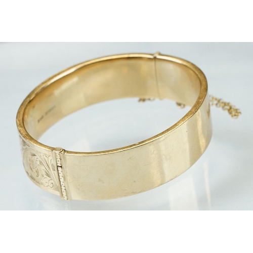 36 - 9ct yellow gold hinged bangle, engraved foliate scroll decoration to the upper half, tongue and box ... 