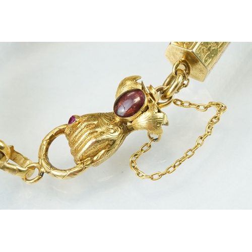 37 - 19th century ruby and garnet yellow metal bracelet, the clasp modelled as a hand holding a ring, cab... 