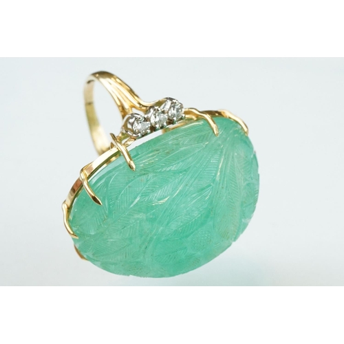 56 - Emerald and diamond yellow metal ring, the large oval cabochon cut emerald with floral and foliate d... 