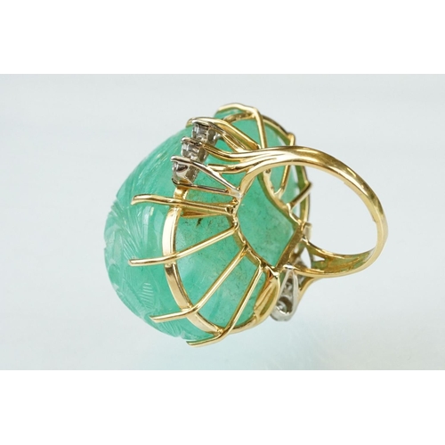 56 - Emerald and diamond yellow metal ring, the large oval cabochon cut emerald with floral and foliate d... 