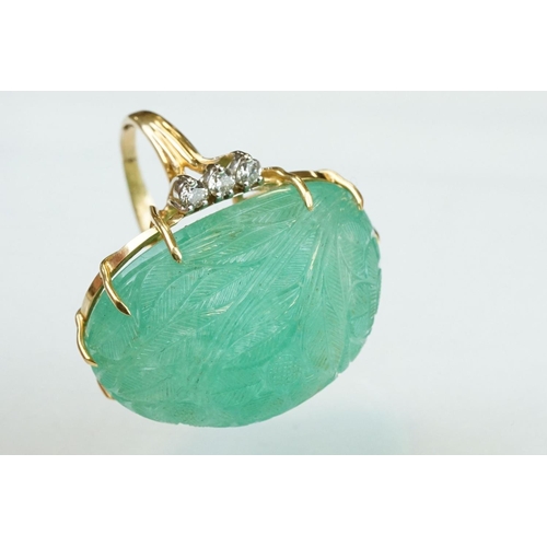 56 - Emerald and diamond yellow metal ring, the large oval cabochon cut emerald with floral and foliate d... 