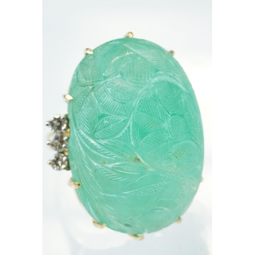 56 - Emerald and diamond yellow metal ring, the large oval cabochon cut emerald with floral and foliate d... 