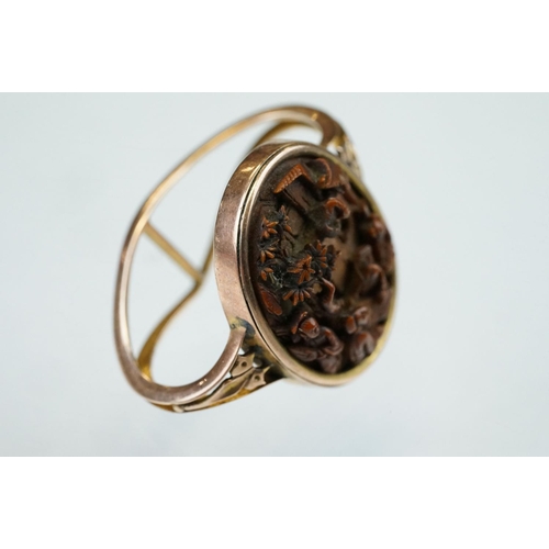 71 - Oriental resin rose metal scarf ring, the panel depicting elders sat around a table in village scene... 