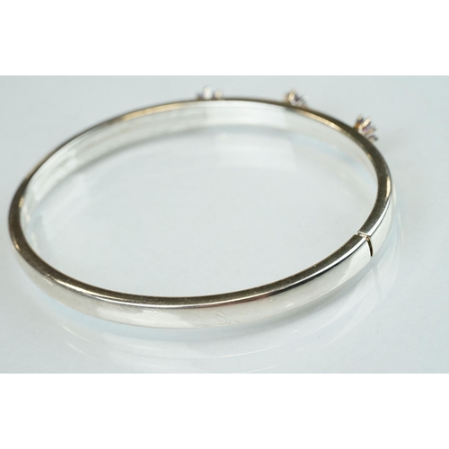 98 - Four silver hinged bangles, together with a Rennie Macintosh style cubic zirconia set silver bangle ... 