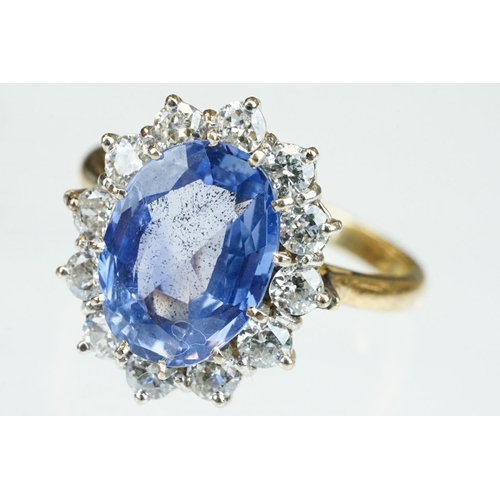 16 - Sapphire and diamond 18ct yellow and white gold set cluster ring, the oval mixed cut sapphire measur... 