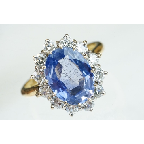 16 - Sapphire and diamond 18ct yellow and white gold set cluster ring, the oval mixed cut sapphire measur... 