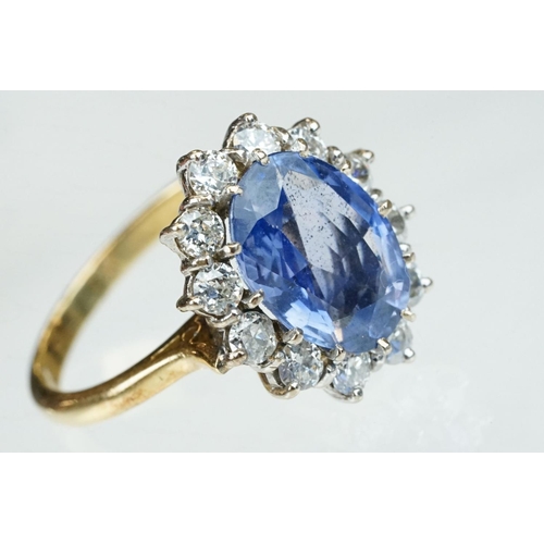 16 - Sapphire and diamond 18ct yellow and white gold set cluster ring, the oval mixed cut sapphire measur... 