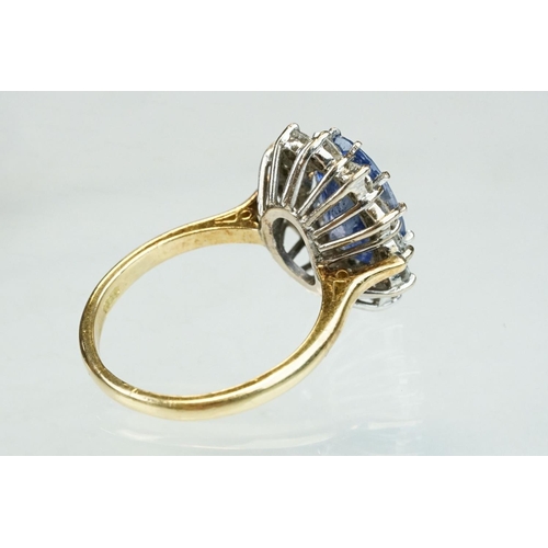 16 - Sapphire and diamond 18ct yellow and white gold set cluster ring, the oval mixed cut sapphire measur... 