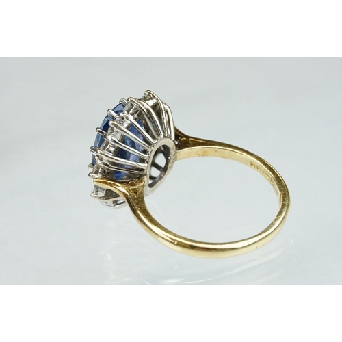 16 - Sapphire and diamond 18ct yellow and white gold set cluster ring, the oval mixed cut sapphire measur... 