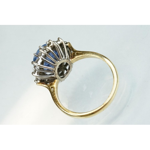 16 - Sapphire and diamond 18ct yellow and white gold set cluster ring, the oval mixed cut sapphire measur... 