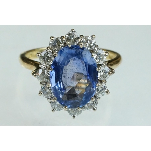 16 - Sapphire and diamond 18ct yellow and white gold set cluster ring, the oval mixed cut sapphire measur... 