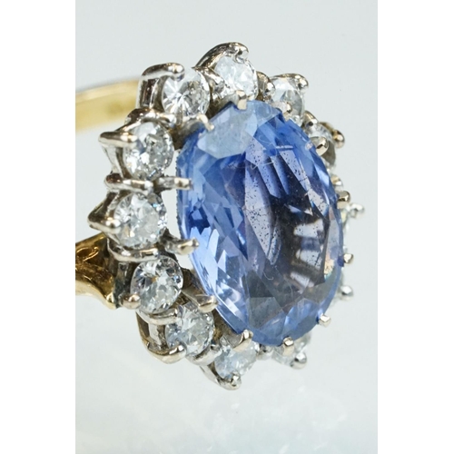 16 - Sapphire and diamond 18ct yellow and white gold set cluster ring, the oval mixed cut sapphire measur... 