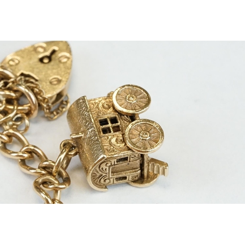 200A - 9ct yellow gold charm bracelet with padlock clasp and safety chain, eleven 9ct gold charms and one y... 