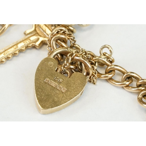 200A - 9ct yellow gold charm bracelet with padlock clasp and safety chain, eleven 9ct gold charms and one y... 