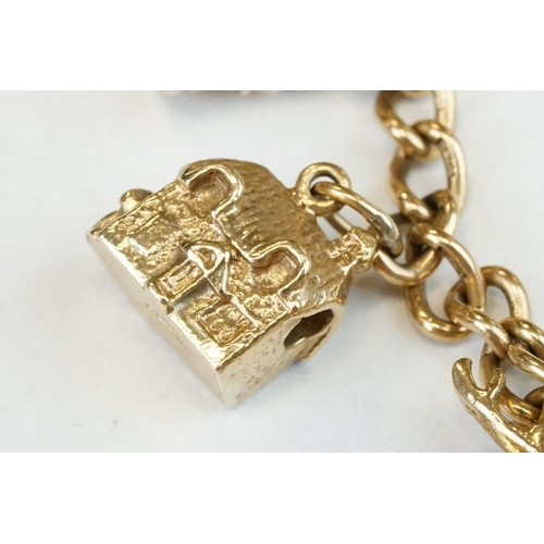 200A - 9ct yellow gold charm bracelet with padlock clasp and safety chain, eleven 9ct gold charms and one y... 