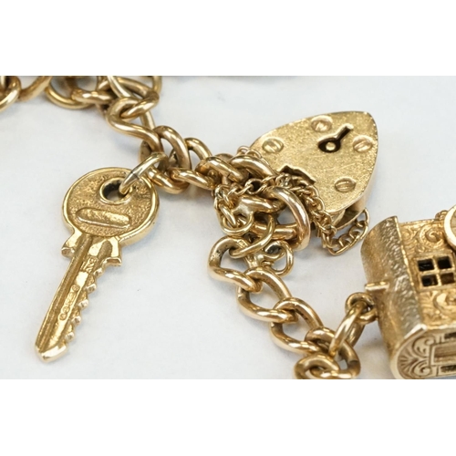 200A - 9ct yellow gold charm bracelet with padlock clasp and safety chain, eleven 9ct gold charms and one y... 