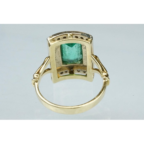 4 - Emerald and diamond unmarked yellow gold ring, the emerald cut emerald measuring approx 11mm x 7mm, ... 