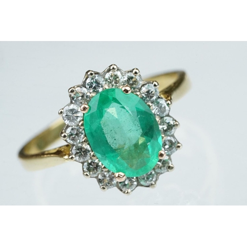 7 - Emerald and diamond unmarked yellow gold cluster ring, the oval mixed cut emerald measuring approx 1... 