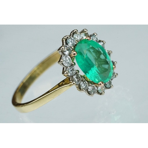 7 - Emerald and diamond unmarked yellow gold cluster ring, the oval mixed cut emerald measuring approx 1... 