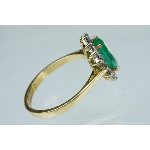 7 - Emerald and diamond unmarked yellow gold cluster ring, the oval mixed cut emerald measuring approx 1... 