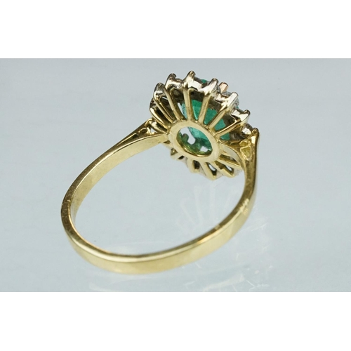 7 - Emerald and diamond unmarked yellow gold cluster ring, the oval mixed cut emerald measuring approx 1... 