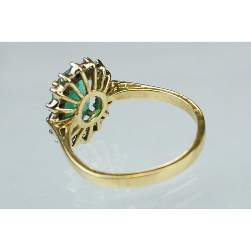 7 - Emerald and diamond unmarked yellow gold cluster ring, the oval mixed cut emerald measuring approx 1... 