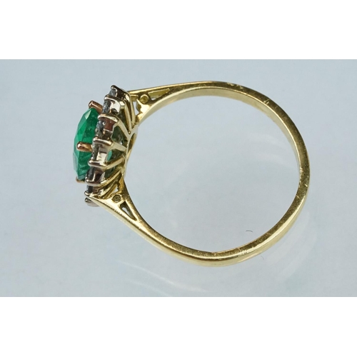 7 - Emerald and diamond unmarked yellow gold cluster ring, the oval mixed cut emerald measuring approx 1... 