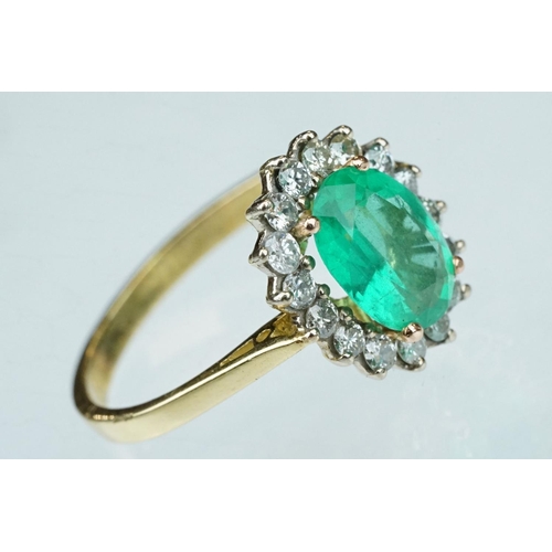 7 - Emerald and diamond unmarked yellow gold cluster ring, the oval mixed cut emerald measuring approx 1... 