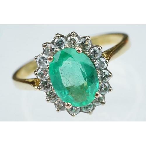 7 - Emerald and diamond unmarked yellow gold cluster ring, the oval mixed cut emerald measuring approx 1... 