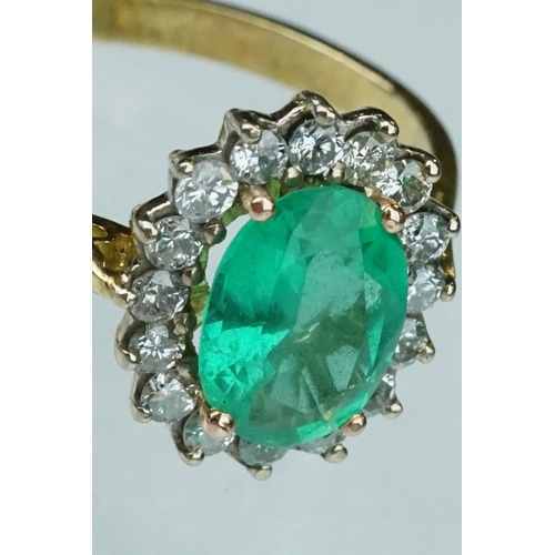 7 - Emerald and diamond unmarked yellow gold cluster ring, the oval mixed cut emerald measuring approx 1... 