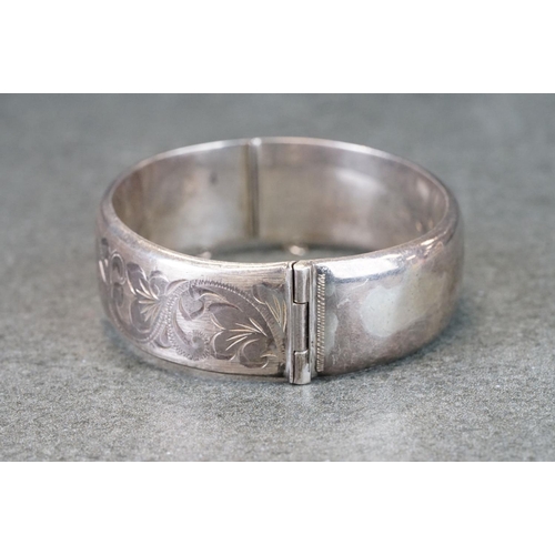 302A - Silver hinged bangle, engraved foliate scrolling decoration, tongue and box clasp, broken safety cha... 