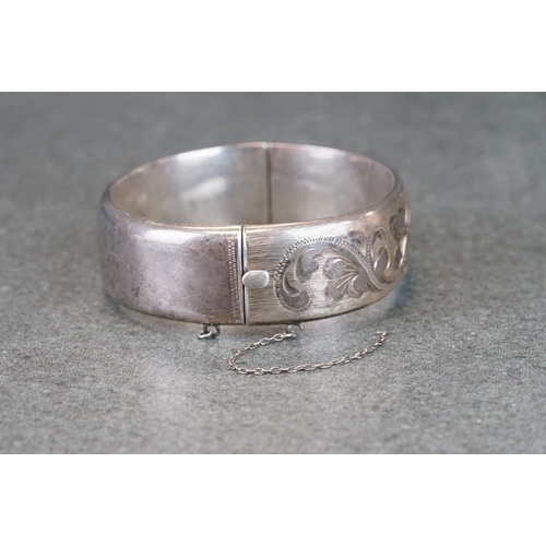 302A - Silver hinged bangle, engraved foliate scrolling decoration, tongue and box clasp, broken safety cha... 