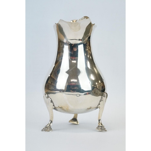 415 - Silver cream jug, the baluster body raised on three hoof feet, scroll handle, ogee rim, makers Jay, ... 