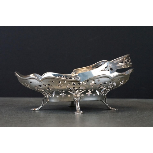 429 - Pair of silver swing handled bon bon dishes raised on four feet, pierced body, scalloped border, mak... 