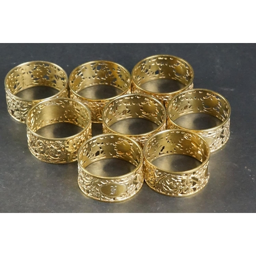 517 - Eight matching silver gilt napkin rings with pierced floral decoration, engraved monograms to cartou... 