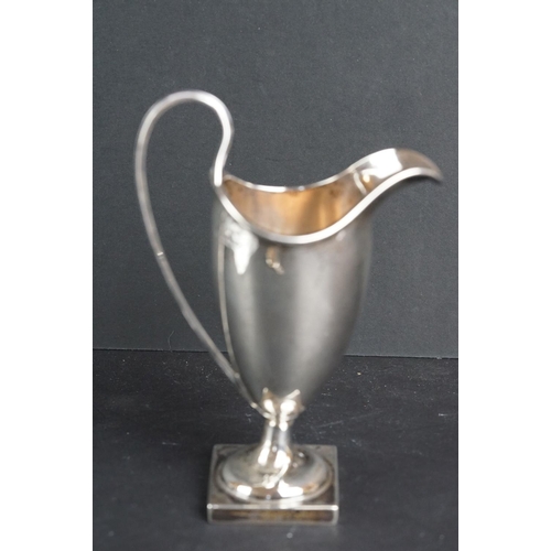 540 - Silver helmet shaped milk jug, the plain polished body raised on moulded circular foot to square ped... 