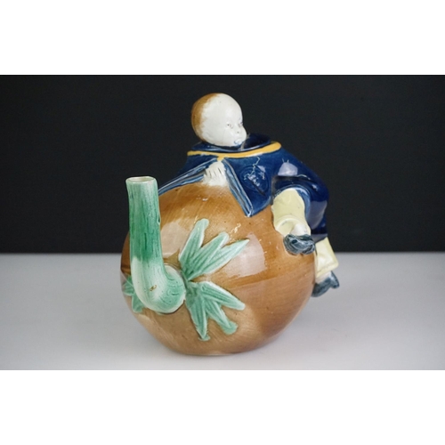 48 - Majolica teapot and cover modelled as a Chinese boy resting on a brown coconut with green glazed spo... 