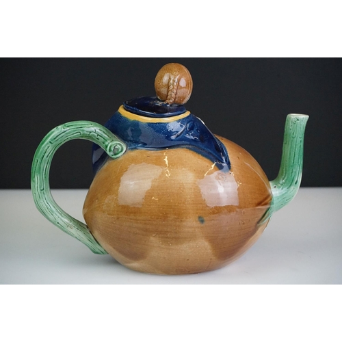 48 - Majolica teapot and cover modelled as a Chinese boy resting on a brown coconut with green glazed spo... 