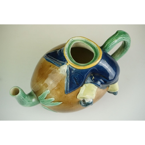 48 - Majolica teapot and cover modelled as a Chinese boy resting on a brown coconut with green glazed spo... 