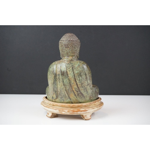 128 - Bronze figure of a Buddha seated in sattvasana clutching a bowl in both hands with a verdigris finis... 