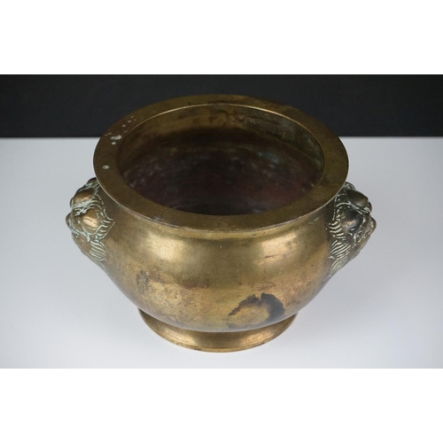 141 - Chinese brass censer with relief dragon mask decoration raised on a circular foot, approx 11cm high