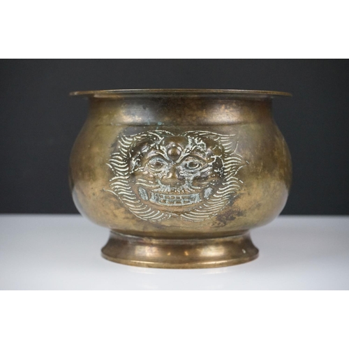 141 - Chinese brass censer with relief dragon mask decoration raised on a circular foot, approx 11cm high