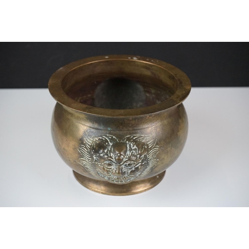 141 - Chinese brass censer with relief dragon mask decoration raised on a circular foot, approx 11cm high