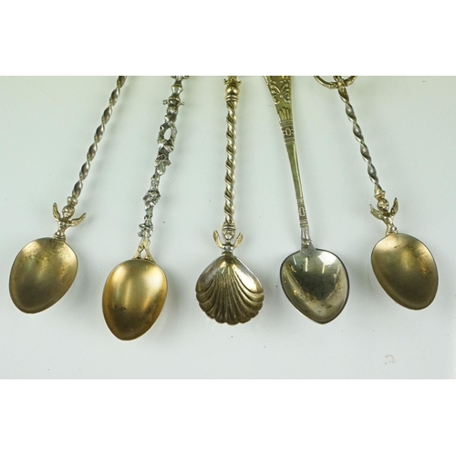 274 - A collection of five white metal teaspoons to include four gilt examples with ornate finials.