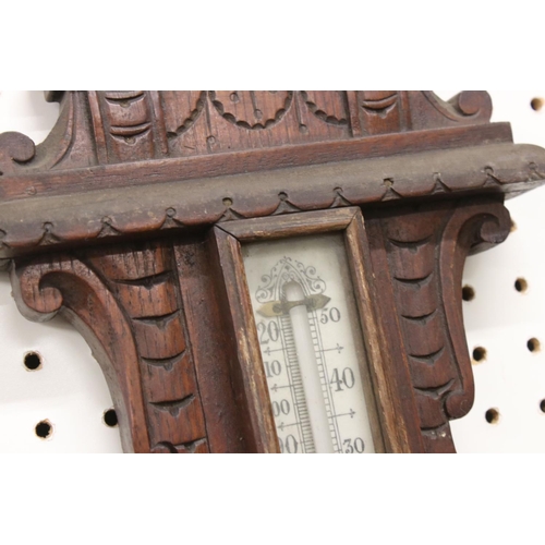 512 - A late 19th / Early 20th Century carved oak wheel barometer, with mercury thermometer and aneroid ba... 