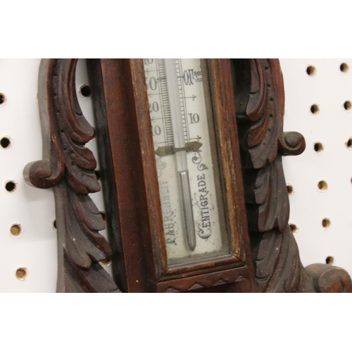 512 - A late 19th / Early 20th Century carved oak wheel barometer, with mercury thermometer and aneroid ba... 