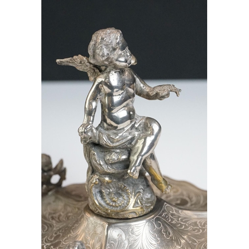 129 - A Victorian silver plated table centrepiece with a winged cherub holding a butterfly above three sha... 