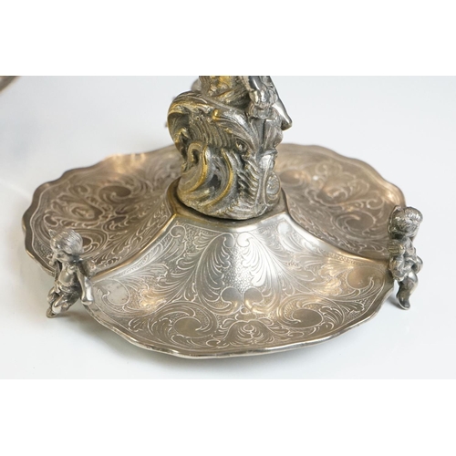 129 - A Victorian silver plated table centrepiece with a winged cherub holding a butterfly above three sha... 