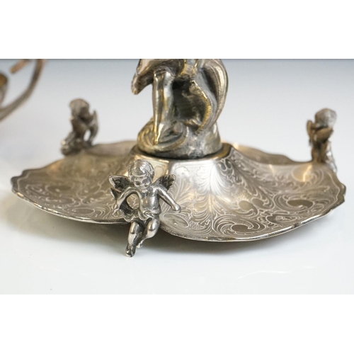 129 - A Victorian silver plated table centrepiece with a winged cherub holding a butterfly above three sha... 